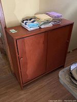 Closed wood cabinet with sliding doors and hand towels on top