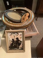 Photo showing a variety of picture frames including a decorative square frame with a floral silhouette image, an oval dark wood frame, a golden circular frame, a small wooden frame with a stand, and a textured rectangular frame.