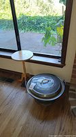 Wooden round accent table next to the bread dough riser near window, showing full size and condition of items