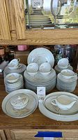 Photo showing entire Norcrest china set including multiple stacks of plates, saucers, teacups, sugar bowl, and creamer with matching wheat floral design.