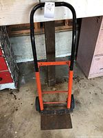 Front view of hand truck with black handle and orange base.