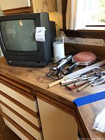 Photo showing Panasonic TV with built-in VHS, immersion blender, terracotta pan, and various kitchen utensils on a countertop.