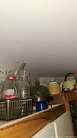 Photo showing decorative bottles including Coca-Cola bottles and glass bottles placed inside a wire basket along with other decor items.
