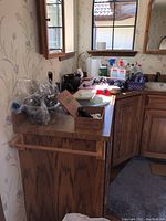 Photo of kitchen-like counter with multiple pocket cutting tools still in plastic, assorted bottles including cleaning sprays and a boxed item.