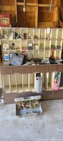 Wide view of wooden cubby shelves containing assorted hardware items, nails, screws, drill cases, and fittings