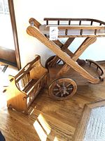 Oak magazine rack beside serving cart displaying curved sides and wood grain.