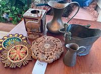 Overview photo of all items on wooden surface showing pitchers, tissue box, trivets, wooden trivet and deer figurine.
