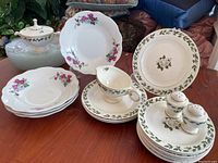 Assortment of floral patterned Superior Hall chinaware including salad and dessert plates, sugar bowl, creamer, and salt and pepper shakers on a wooden table