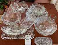 Photo showing multiple floral-themed glass serving bowls and dishes arranged on a wooden table.