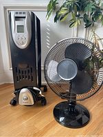 Black oil-filled radiator heater and black tabletop fan shown side by side, heater front view