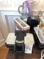 Photo showing part of the lot with Belgian waffle maker, Hamilton Beach cutting utensil in box, food processor and coffee grinder.