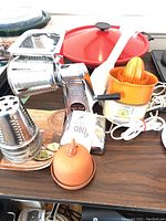 Photo shows the array of kitchen appliances on a table including the juicer, garlic roaster, and electric wok lid.
