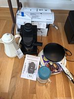 Photo showing Food Saver vacuum sealer with its box, Melitta espresso machine with manual, black electric crepe maker, small Thermos, and insulated coffee carafe.