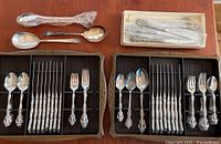 Two plastic storage trays with compartments holding flatware and knives
