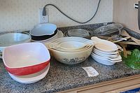 Counter display of Pyrex bowls and dishes in various sizes and colors including floral and solid patterns.