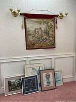 Full view of reproduction Francois Boucher tapestry hanging with five framed art pieces below resting on carpeted floor