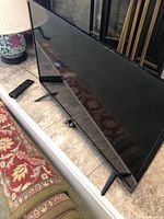 Front and side view of 32-inch Vizio TV with remote on the floor next to it.