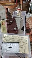 Knife with bone handle, leather sheath, and certificate displayed in box.