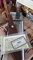 Photo showing knife in box with matching leather sheath and certificate of authenticity.