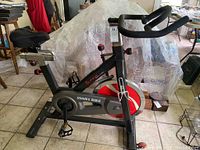 Side view showing the entire Sunny Bike Fitness exercise bike with black frame and red/silver flywheel.