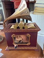 Front and top view of holiday music box with simulated music reels and mouse figurine showing ornate horn and wood detail.