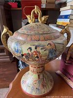 Front angle view of the Japanese decorative lidded vessel showcasing traditional painted scenes and lid handle.