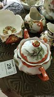 Porcelain set with sugar bowl, creamer, bowl, and pitcher on decorative surface