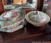Shows the full set of Asian ceramic serving pieces including the lidded platter, footed bowl, small bowl, and large lidded bowl with intricate detailing and colors.