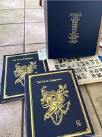 Two large blue hardcover volumes titled 'The Great Composers' with gold embossed text and musical illustrations on cover. Books shown with part of Funk & Wagnalls magazines spread open underneath.
