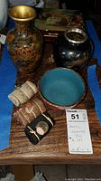 Top view of the decorative vases, jewelry box, blue bowl and small rolled items on wooden surface