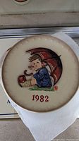 Close-up of 1982 Hummel plate with child holding umbrella illustration