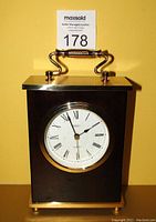 Front view of Birks brass quartz clock showing clock face with Roman numerals and brass handle top