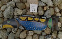 Top view of painted wood carving shaped like a fish with Indigenous motifs.