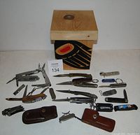 Photo shows the Indigenous Haida cedar artwork wooden box and an array of pocket tools and knives laid out.
