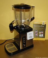 Villa Ware Smoothie Bar appliance with blending pitcher, spout, control panel, and drip tray shown alongside its instruction and recipe book.