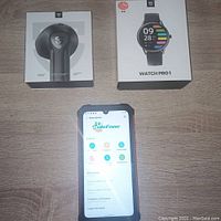Ulefone Armor 8 Pro phone powered on displaying feature list. SoundPEATS wireless earbuds box and Watch Pro 1 box shown.