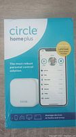 Front view of factory-sealed Circle Home Plus parental control device packaging showing product image and smartphone app interface.