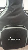 Close-up of front pocket on black padded soft carrying case with 'Donner' logo in white