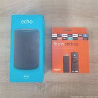 Photo of original boxed Amazon Echo smart speaker and boxed Fire TV Stick Lite