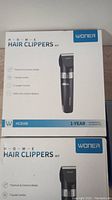 Photo of two factory-sealed WONER Home Hair Clippers Kits stacked, showing product name, specifications, and model HC816B on white and blue packaging.