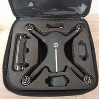 Zippered foam carrying case opened to show drone body, two batteries, and remote controller.