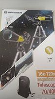 Front of retail box showing Bresser branding, telescope on tripod and backpack illustration, magnification and model specs.