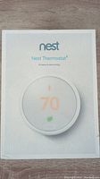 Front of retail box showing Nest logo and thermostat image