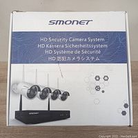 White SMONET box labeled 'HD Security Camera System' showing four bullet cameras and a black NVR