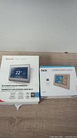 Photo of both Honeywell Wi-Fi Smart Colour Thermostat and FanJu Wireless Weather Station in their original packaging.