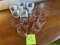 Photo of 12 Christmas cocktail glasses arranged in groups on a wooden surface, showing different festive designs.