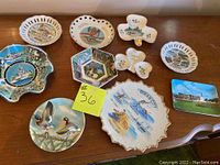 Photo showing 10 various collectors plates with detailed painted and printed scenes featuring ships, birds, coastal views, airplanes, and estates.