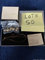 Boxed set showing gold balls in plastic bag, gold necklace, Sarah Coventry box, and informational card.
