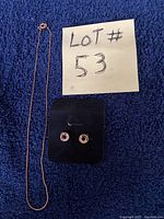 16-inch gold-tone chain necklace alongside matching circular hoop earrings displayed on black velvet mount with lot number note on blue fabric background.