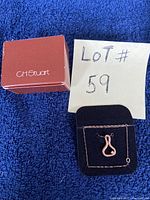 Photo of the necklace with pendent on black cushion mount with handwritten lot number '59' and CH Stuart box nearby.